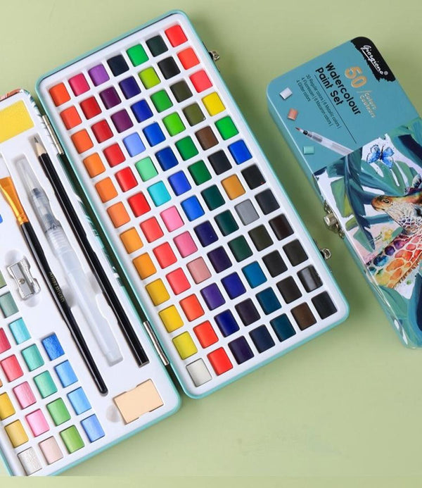 Set of watercolor paints in a metal case with brushes on a green background