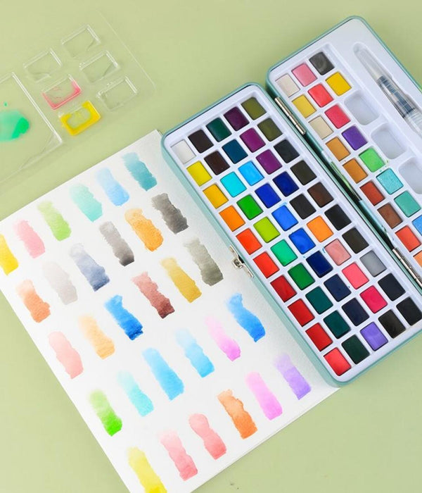 Open watercolor set with a variety of colors on a light green background