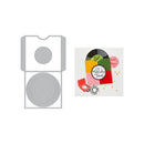 A die-cut craft template or cardstock layout shown on a white background, with a gray metal template on the left and a colorful example card design on the right featuring a vinyl record, gift box, and holiday cards.