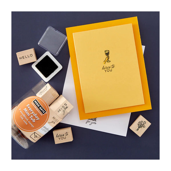 Yellow card with 'here to you' text, rubber stamps, and ink pad on a dark blue background
