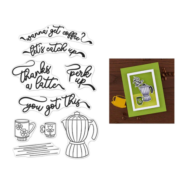 Coffee-themed clear stamps with various phrases and a coffee maker stamp, alongside a framed artwork on a wooden surface.
