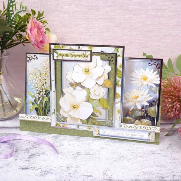 Floral card with white flowers on a wooden surface with flowers and ribbons.
