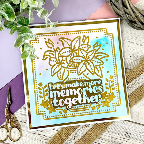 Decorative card with floral design and text 'Let's make more memories together' on a wooden surface with decorative elements.