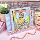 Colorful greeting card with a vintage-style illustration of a woman, text 'You don't look a day over Fabulous' on a decorative surface with flowers and ribbons.