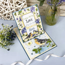 Greeting card with birds and flowers on a light blue surface with decorative elements.