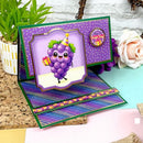 Colorful greeting card with a cartoon grape character on a decorative surface with flowers and plants.