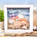 Framed artwork with seashells and a wooden signpost on a beach background
