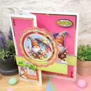 Colorful greeting card with a gnome design on a pink background, surrounded by plants and Easter eggs.