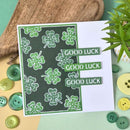 Card with green four-leaf clover pattern and 'Good Luck' text on a wooden surface with buttons.