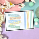 Card with 'THANK YOU' text in pastel colors on a colorful background with flowers and pom-poms.