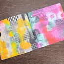 Two colorful art notebooks on a wooden surface