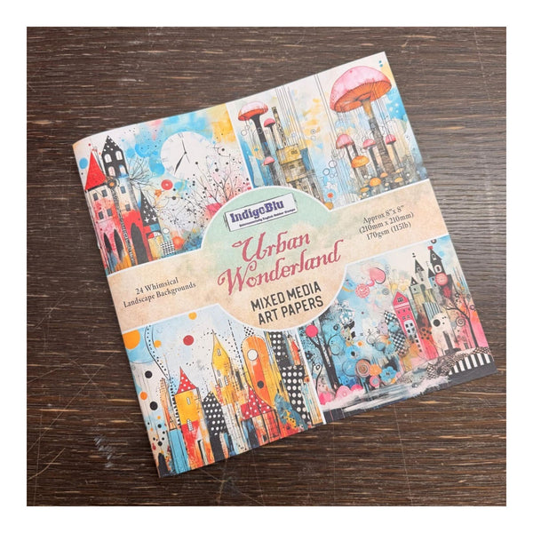 Pack of mixed media art papers with colorful illustrations on a wooden surface