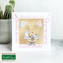 Baby shower card with teddy bear illustration and 'It's a Girl' text, placed on a white surface with a cactus plant in the background.