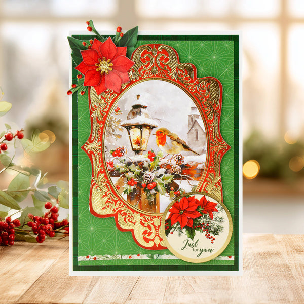 Decorative Christmas card with red poinsettias and a lantern design on a wooden surface.
