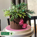 Decorative cake with a woven basket and greenery on a pink platform, featuring Katy Sue Design Team Inspiration text.