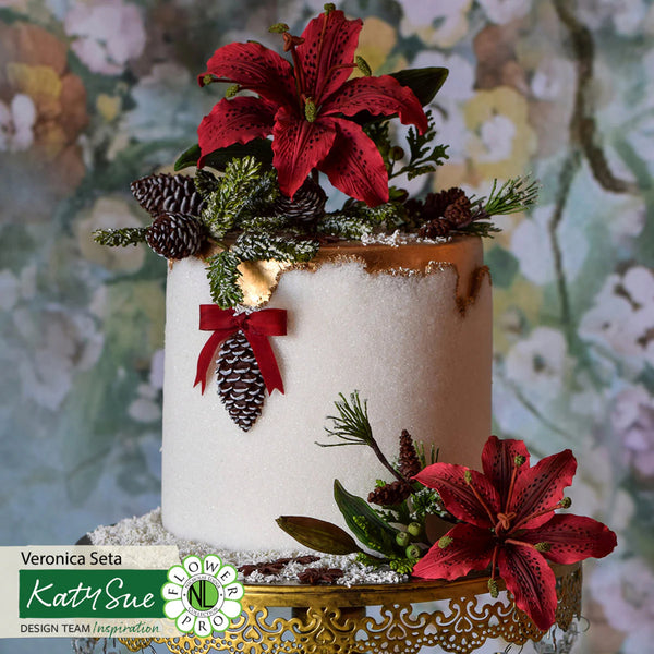 Decorative cake with red flowers, pinecones, and greenery against a floral background