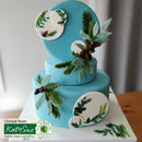 Two-tiered blue cake with floral decorations on a white surface.