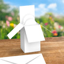 White windmill model on a wooden surface with a blurred natural background