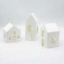 Three white paper house models with cut-out windows and doors on a light gray background