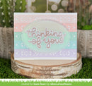 Greeting card with 'thinking of you' text on a decorative stand with plants in the background