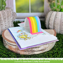 Colorful card with rainbow and cloud design on a wooden block with plants in the background
