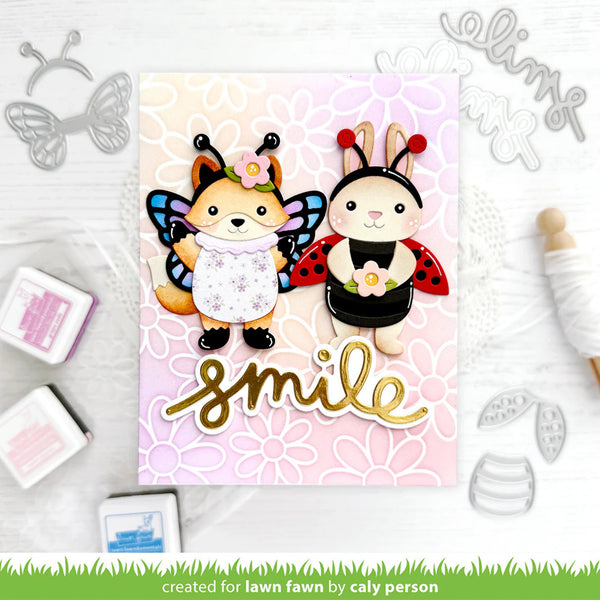 Card with cartoon fox and rabbit characters wearing insect costumes, surrounded by crafting supplies.