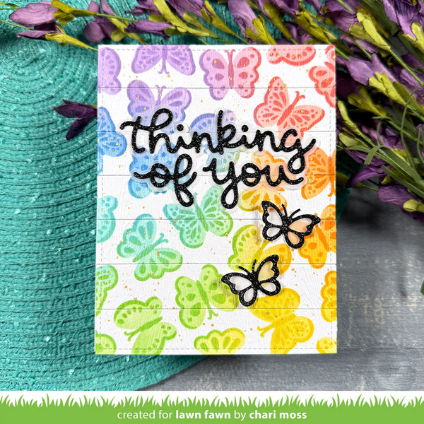 Card with colorful butterfly design and 'thinking of you' text, surrounded by flowers.