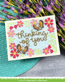 Card with butterflies and flowers on a textured surface with flowers in the background