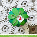 Green paper shamrock with a red heart tag on a lace doily background