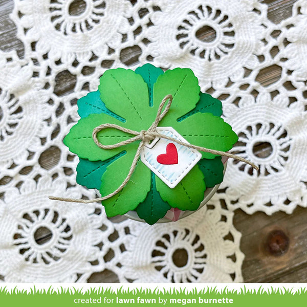 Green paper shamrock with a red heart tag on a lace doily background