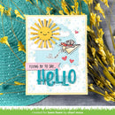 Greeting card with sun and airplane design, text 'Flying by to say Hello', surrounded by yellow flowers on a textured surface.