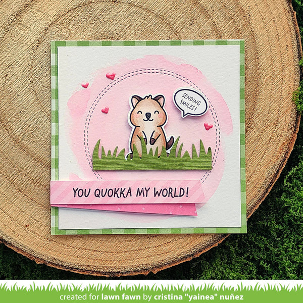 Card with a quokka design and text 'You quokka my world!' on a wooden surface.
