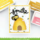 Card with bee and beehive design and 'smile' text, surrounded by ink pads and tools.