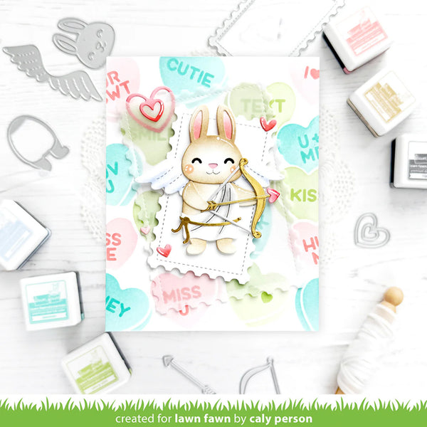 Card with a cute bunny holding a bow and arrow, surrounded by stamping tools on a white background.