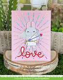 Card with a cartoon bunny holding a bow and arrow on a pink background with 'love' text, placed on a wooden stand with a cactus and succulent plant in the background.