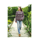 Woman walking on a wooden bridge over a pond with striped sweater and jeans