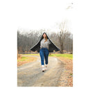 Woman walking on a path in a forest wearing a hooded vest.