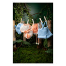 Crocheted baby outfit with hat, romper, and overalls hanging on a clothesline against a natural background.