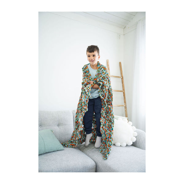 Person wearing a colorful robe in a cozy room with a white wall and gray sofa.