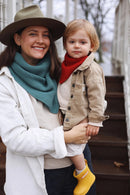 Woman holding a child outdoors, both wearing scarves and coats