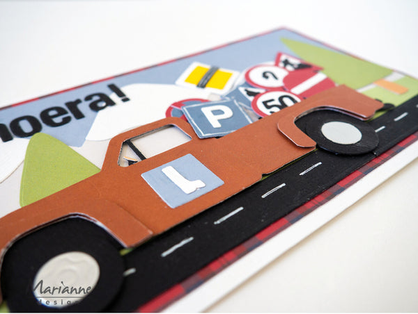 Decorative paper cutout of a car with road and traffic sign elements on a white background.