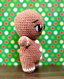 Crocheted gingerbread man amigurumi against a polka dot background