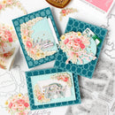 Decorative greeting cards with floral designs and text on a white surface with craft materials.