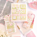 Decorative sticker sheets with building designs and floral elements on a light pink background.