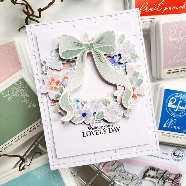 Card with decorative bow and flowers, surrounded by craft supplies.