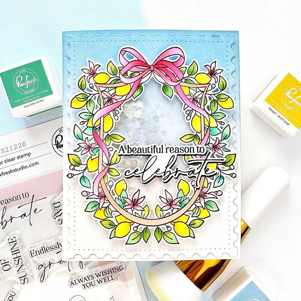 Card with floral wreath design and 'A beautiful reason to celebrate' text, surrounded by stamps and stamping supplies.