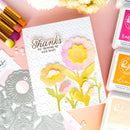Card with floral design and crafting supplies on a pink surface