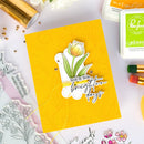 Yellow card with floral design and text, surrounded by stamping supplies on a light background