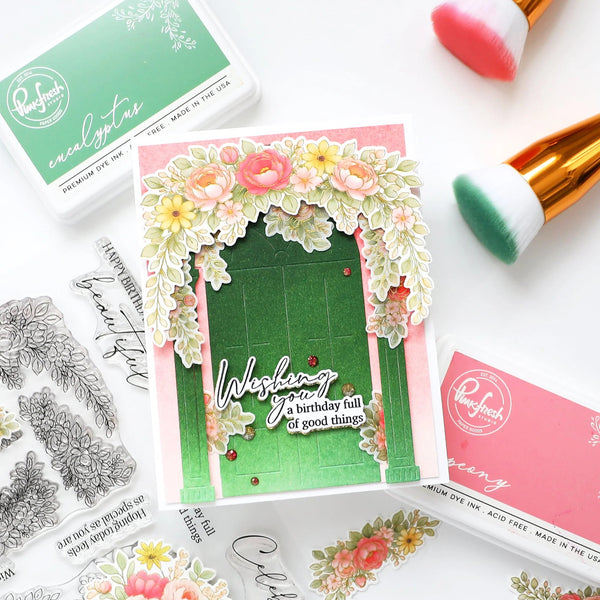 Handmade card with floral design and 'Wishing you a birthday full of good things' text, surrounded by stamping supplies.