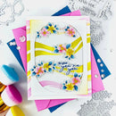 Colorful card with floral design and text, surrounded by crafting tools on a white background